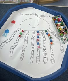 a child's drawing of a jellyfish on a paper plate with beads in it