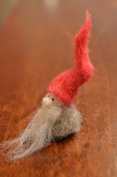 a small red and white gnome sitting on top of a wooden table