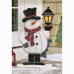 a snowman with a hat and scarf standing in front of a light on the porch