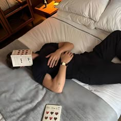 a woman laying on top of a bed next to two cards and a remote control