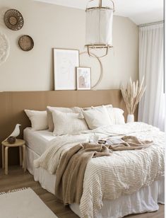 a bed with white linens and pillows in a bedroom next to a wooden floor