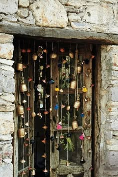 an old door with many bells hanging from it's sides and a stone wall behind it