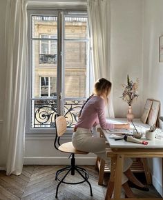 a woman sitting at a desk in front of a window