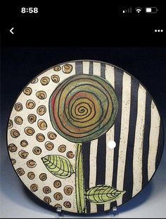 a ceramic plate with a flower painted on it's side and stripes in the background