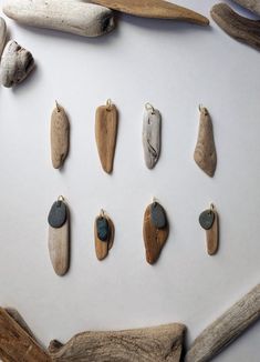 several different types of wood and stone hanging from hooks on a white surface next to driftwood