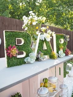 the letters are decorated with flowers and succulents on top of a shelf