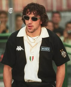 a man with sunglasses and a black shirt is standing in front of a group of people