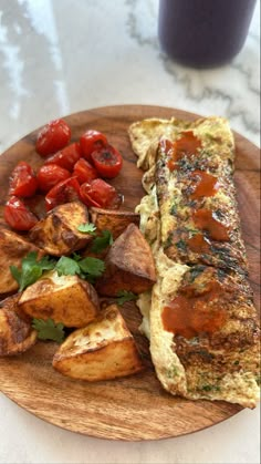 an omelet, potatoes and tomatoes on a wooden plate