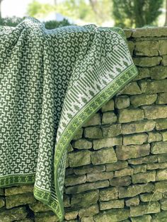 a green and white blanket sitting on top of a stone wall