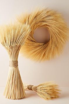 two straw brooms sitting next to each other on a white surface