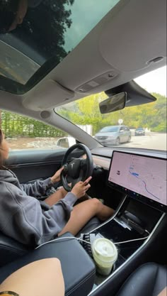 a woman sitting in the driver's seat of a car using a laptop computer