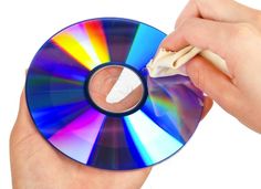 a person holding a cd in their left hand and cleaning the disc with a cloth