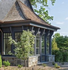 a house that has a tree in front of it and some bushes around the corner