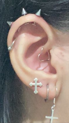 a close up of a person's ear with piercings and crosses on it