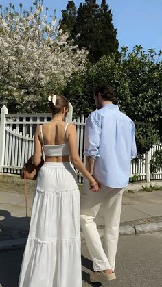 a man and woman walking down the street holding hands