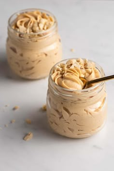 two jars filled with peanut butter on top of a white counter next to each other