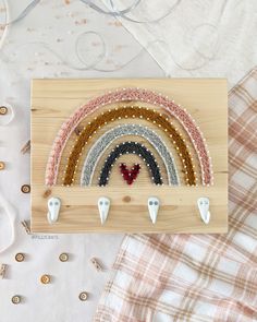 a wooden frame with beads and scissors in it on top of a bed next to other items