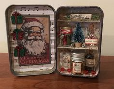 two tins with christmas decorations on them sitting on top of a wooden table next to each other