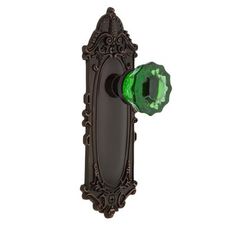 an ornate door handle with a green glass knob on the front and back of it