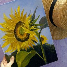 a painting of a sunflower being held up by someone's hand with a straw hat on top