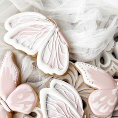 cookies decorated with pink and white butterflies are on a lace tablecloth, next to some tulle