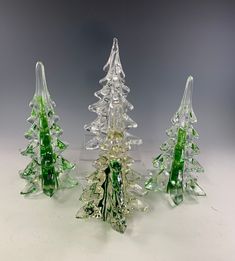 three glass christmas trees sitting next to each other