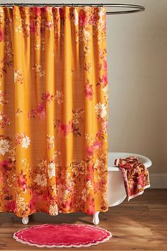 an orange shower curtain with pink flowers on it and a red rug in front of it