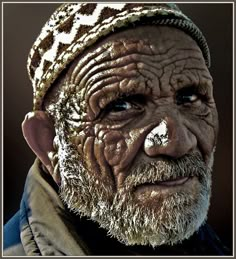 an old man with wrinkles on his face and beard is looking at the camera