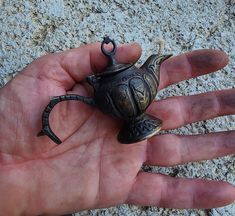 a small teapot sitting on top of someone's hand