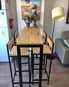 a kitchen table with four stools and a painting on the wall