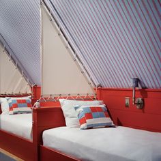 there are two beds in the room with red walls and blue blinds on the roof