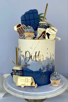 there is a blue and white cake with gold decorations on the top that says, dad