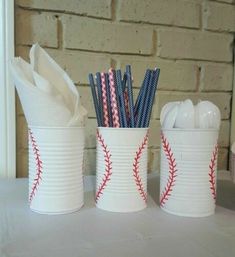 three baseball themed cups with paper straws and toothbrushes in them on a table