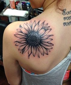 a woman with a sunflower tattoo on her upper back shoulder and the words, even when you're over out