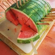 a watermelon slice being cut into smaller pieces with toothpicks on them