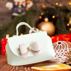 a white purse sitting on top of a wooden table next to christmas decorations and pine cones