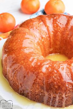 a glazed bunt cake sitting on top of a white plate next to oranges