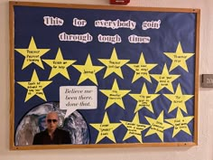 a bulletin board with yellow stars and a man's face in the center surrounded by words