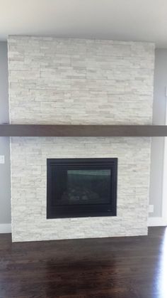 an empty living room with a fireplace in the center and wood flooring on the other side