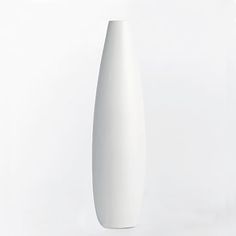 a tall white vase sitting on top of a table