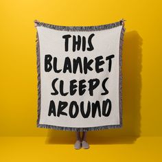 a woman holding up a sign that says, this blanket sleeps around on yellow background