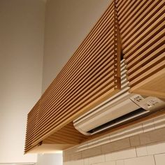 a white air conditioner sitting on top of a wooden shelf