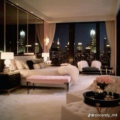 a living room filled with lots of furniture and tall buildings in the background at night