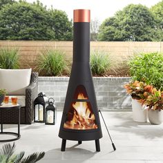 an outdoor fireplace in the middle of a patio with potted plants and chairs around it