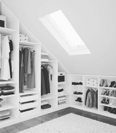 an attic closet with white shelving and shelves filled with clothes, shoes and other items