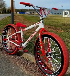 a red and white bicycle parked on the side of a road