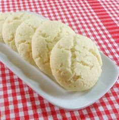 three cookies on a white plate sitting on a red and white checkered tablecloth