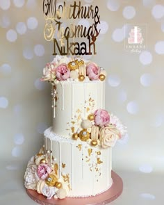 a three tiered wedding cake with flowers on the top and gold lettering that reads, mr and mrs thir & tamu's mukah