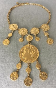 You are looking at a truly spectacular and exquisite VINTAGE TRIFARI Gold-tone Metal ROMAN COIN PENDANT CHARM BIB NECKLACE that features different sizes of coins depicting the profile of a Roman Emperor to create a massive bib that is 6” in total length, in a Baroque design with an Art Deco inspiration, SIGNED, Circa 1970's.MASSIVE AND SUPER RARE STATEMENT PIECE IN MINT AND FLAWLESS, NEVER USED VINTAGE CONDITION!!!!INCREDIBLY ELEGANT AND TRULY SPECTACULAR!!!! A TRUE WORK OF ART!!!!This superb ne Vintage Coin Necklaces For Festival, Vintage Metal Necklace With Coin Pendant, Vintage Metal Coin Pendant Necklace, Vintage Ceremonial Jewelry With Coin Pendant, Vintage Metal Coin Necklace, Vintage Necklace With Coin Pendant, Vintage Coin Necklaces, Vintage Ceremonial Coin Necklaces, Vintage Ceremonial Coin Necklace