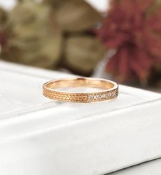 a gold wedding band with five diamonds on it sitting on top of a white surface